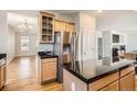 Kitchen island with stainless fridge, granite counters and modern cabinets open to the dining and living area at 20964 E Greenwood Pl, Aurora, CO 80013