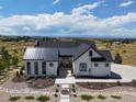 Modern farmhouse with a metal roof, expansive windows, and a landscaped yard sits on a large lot with mountain views at 8263 Merryvale Trl, Parker, CO 80138