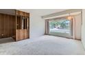 Bright living room featuring neutral carpet, wood paneled wall, and large picture window at 2122 S Yank Way, Lakewood, CO 80228