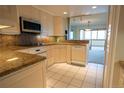 Kitchen features white cabinets, granite countertops and white appliances, seamlessly flowing into the living area at 3131 E Alameda Ave # 1604, Denver, CO 80209