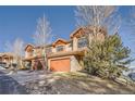 Two-story home with stone accents, a two-car garage, and beautiful trees in the yard at 995 Nob Hill Rd, Evergreen, CO 80439