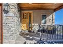 Inviting front porch featuring stone accents, a wooden ceiling, and a cozy seating area at 995 Nob Hill Rd, Evergreen, CO 80439