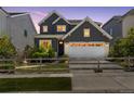 Beautiful gray two-story home at twilight, featuring a white garage door, manicured lawn, and split rail fence at 13334 Blue Amber Ct, Parker, CO 80134