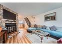 Cozy living room featuring stone fireplace, modern sofa, and staircase to the second floor at 14486 E Hawaii Cir # D, Aurora, CO 80012