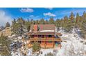 Exterior view of a two-story log home with wrap-around deck at 10658 Tallberg Ln, Conifer, CO 80433