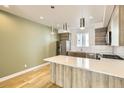 Open-concept kitchen with stainless steel appliances, pendant lighting, and light hardwood floors at 1810 Irving St # 4, Denver, CO 80204