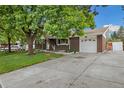 Spacious driveway leading to a two-car garage complements this brick home with mature trees at 8137 Vanguard Dr, Denver, CO 80221