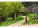 Rustic wooden gate marking the entrance to a long winding driveway through a lush landscape at 245 N County Highway 67, Sedalia, CO 80135
