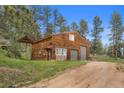 Spacious two-car garage with wood siding and stone accents, complemented by a green lawn at 245 N County Highway 67, Sedalia, CO 80135