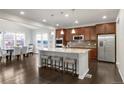 Open-concept kitchen with stainless steel appliances, a large island with seating, and adjacent dining area at 12563 Grape St, Thornton, CO 80241