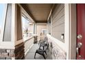 Inviting covered front porch showcases stone pillars, white railing, and cozy seating for relaxing outdoors at 12563 Grape St, Thornton, CO 80241