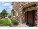 Inviting front entry with brick detail, a dark front door, and manicured landscaping at 10067 Bluffmont Ct, Lone Tree, CO 80124
