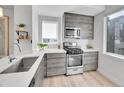 Bright kitchen boasts gray wood cabinets, white countertops, and stainless steel appliances at 1007 Chase St, Lakewood, CO 80214