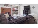 Cozy living room with a brick fireplace, dark sofa, and sliding doors to the balcony at 14439 E 1St Dr # C11, Aurora, CO 80011