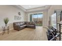 Bright living room with hardwood floors, a large brown leather sofa, and a sliding glass door to a balcony at 7881 W 51St Ave # B, Arvada, CO 80002