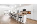 Bright kitchen featuring an island with barstool seating, stainless steel appliances, and white cabinetry at 4730 S Acoma St, Englewood, CO 80110