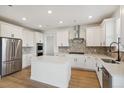 Modern kitchen with stainless steel appliances, white cabinetry, a center island, and hardwood floors at 5439 Westin Hills Dr, Elizabeth, CO 80107