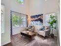 Bright living room featuring vaulted ceilings, large windows, stylish decor, and plush carpeting at 12653 Jersey E Cir, Thornton, CO 80602