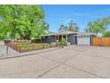 Charming single story home with a large concrete driveway and a well-manicured lawn at 2598 Teller St, Lakewood, CO 80214