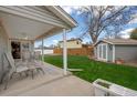 Spacious backyard with a covered patio, lush lawn, privacy fence, and storage shed at 7472 Jay Ct, Arvada, CO 80003