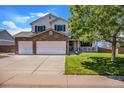 Daytime view of a charming two-story home featuring a stone-accented facade, a well-manicured lawn, and a three-car garage at 1325 Kingsfield St, Castle Rock, CO 80104