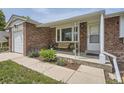 Close-up of the home's entrance featuring a cozy front porch with a bench and landscaping at 10633 E 6Th Pl, Aurora, CO 80010