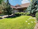 Inviting front yard with healthy lawn, rock feature, and colorful daisylike flowers at 10553 Adams St, Northglenn, CO 80233