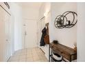 Bright foyer with tile flooring, coat closet, and decorative shelf at 15475 Andrews Dr # 318, Denver, CO 80239