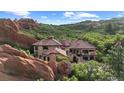 Exterior view of a luxury home with red rock formations and lush greenery in the background at 3755 N Rampart Range Rd, Littleton, CO 80125