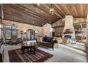 Spacious living room with stone walls, wooden ceiling, stone fireplace and luxury furniture at 3755 N Rampart Range Rd, Littleton, CO 80125