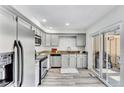 Well-lit kitchen with stainless steel appliances, modern countertops, gray cabinets, and access to the backyard at 7707 S Curtice Way # D, Littleton, CO 80120