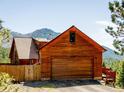 Exterior of wood cabin garage with a large door, set against a backdrop of mountains and trees at 750 Cougar Dr, Boulder, CO 80302