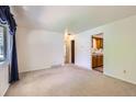 Neutral living room with carpet, a window with dark blue drapes, and views to kitchen and hallway at 912 S Kingston St, Aurora, CO 80012