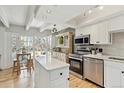 Bright open kitchen with stainless steel appliances, white cabinets, light wood flooring, and a center island at 33 N Corona St # 401, Denver, CO 80218