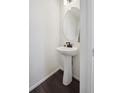 Small bathroom features a pedestal sink, modern faucet, oval mirror, and dark vinyl flooring at 10011 Yampa Ct, Commerce City, CO 80022