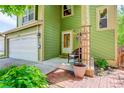 Inviting covered porch with cozy seating, brick pathway, and well manicured landscaping at 7840 S Windermere Cir, Littleton, CO 80120