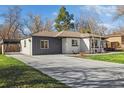 Exterior view of home with a spacious driveway and carport, complemented by a well-maintained lawn and landscaping at 7320 W 21St Ave, Lakewood, CO 80214