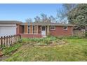 Charming brick home with a well-manicured front yard and white-trimmed windows; garage attached at 1740 S Estes St, Lakewood, CO 80232