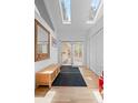 Bright entryway featuring skylights, wood floors, bench, and closet space at 649 Cottonwood Dr, Evergreen, CO 80439