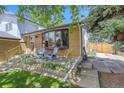 Brick home with an outdoor patio that features chairs and lush landscaping at 13695 W 67Th Cir, Arvada, CO 80004