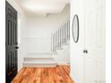 Bright entryway with hardwood floors, a staircase leading to the upper level, and a stylish black front door at 7795 E Kenyon Ave, Denver, CO 80237