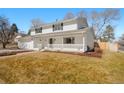 Beautiful home featuring a covered front porch and an attached garage, surrounded by a lush lawn and mature trees at 7795 E Kenyon Ave, Denver, CO 80237
