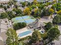 Aerial view showcasing tennis courts, pool, and community buildings surrounded by lush trees at 5745 W Atlantic Pl # 108, Lakewood, CO 80227