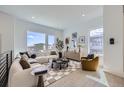 Bright living room features modern furniture, stylish decor, light wood floors, and large windows with neighborhood views at 657 Harness St, Erie, CO 80516