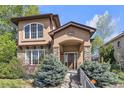 Charming home with stone accents and a well-maintained lawn, showcasing its inviting entrance at 8053 E Maple Ave, Denver, CO 80230