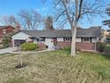 Single-story home featuring a brick facade, well-kept lawn, and mature trees under a bright blue sky at 4152 S Vrain St, Denver, CO 80236