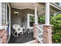 Inviting front porch features a rocking chair and white pillars accented by stonework for an attractive, relaxing entryway at 5491 S Youngfield W Ct, Littleton, CO 80127