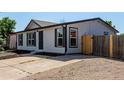 Clean one-story home with a spacious parking area, white siding, and black trim at 657 Locust Ave, Lochbuie, CO 80603