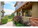 Inviting townhouse entrance with a covered porch, brick foundation, and well-manicured landscaping at 10134 Bluffmont Ln, Lone Tree, CO 80124
