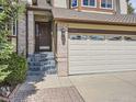 Inviting front entrance with brick accents, marbled steps, and a three car garage to the right at 9412 La Quinta Way, Lone Tree, CO 80124